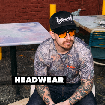 I man wearing a camo shirt and black hat with 'HEADWEAR' overlayed