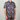 Person wearing a colorful floral patterned shirt on a plain background