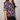 Person wearing a colorful floral patterned shirt against a plain background