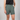 person wearing green shorts and a black shirt with a plain background