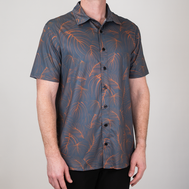 Person wearing a patterned shirt with orange designs on a plain background