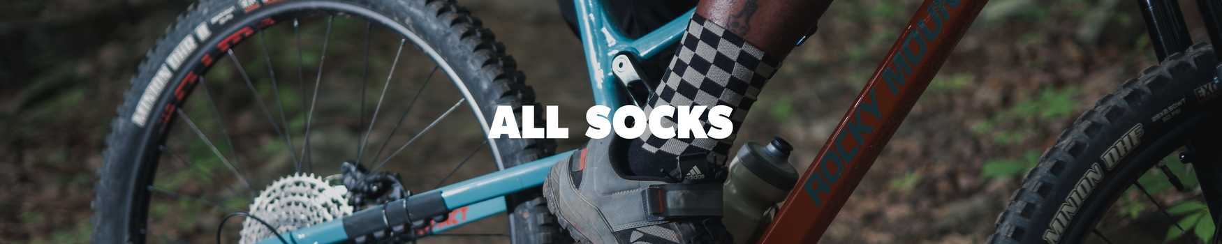 Close-up of a mountain bike with a person wearing checkered socks, text 'ALL SOCKS' overlayed.
